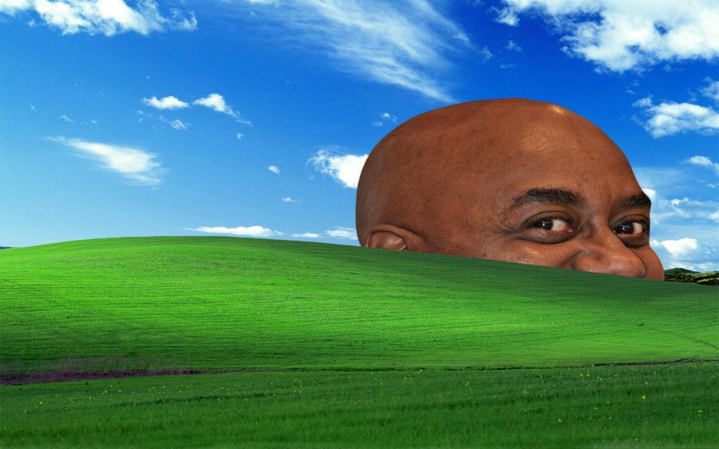 Surreal Windows XP Bliss wallpaper with giant smiling bald man over green hill and blue sky