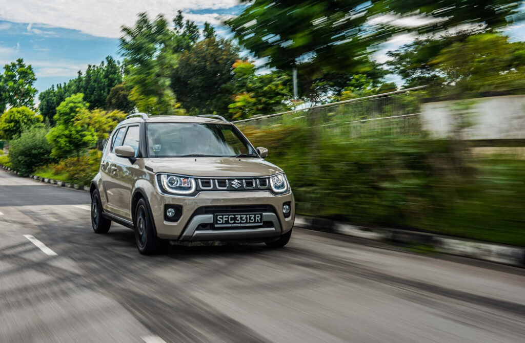 Suzuki car speeding on road with lush green trees vibrant dynamic energetic driving scene wallpaper