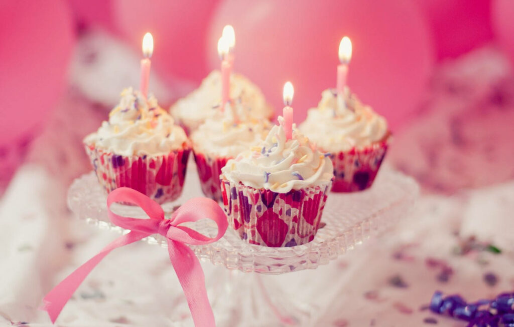 Deliciously Decorated Birthday Mini Cakes Adorned with Candles and Ribbon on Display Wallpaper