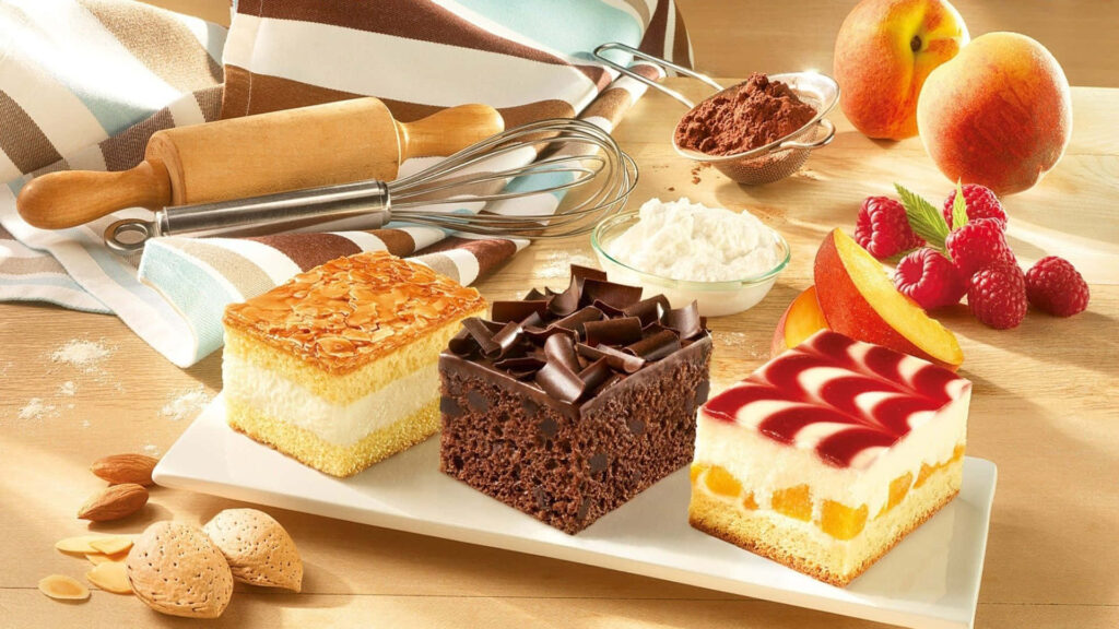 Baking Delights: A Tempting Tray of Assorted Cakes Amidst Scenic Sweetness Wallpaper