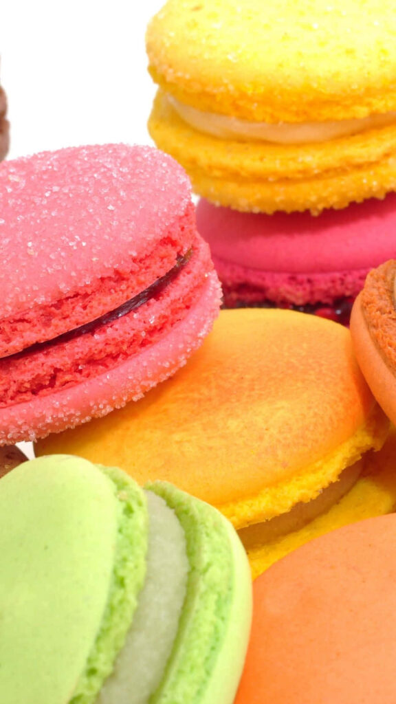 Delightful Desserts: Vibrant Macarons on a Sugary Canvas Wallpaper