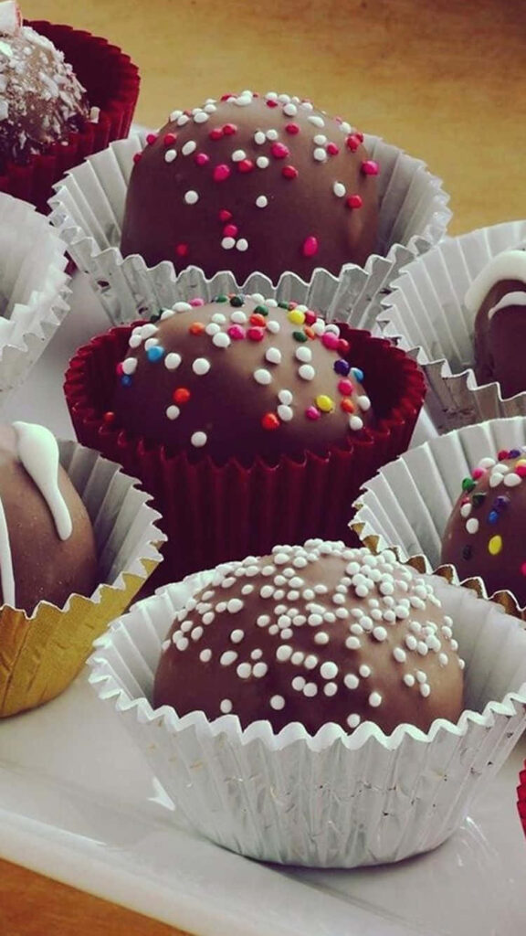 Dessert Delight: Chocolate Truffles with Rainbow Sprinkles, Nestled in Sweet Cupcake Wrapper Wallpaper