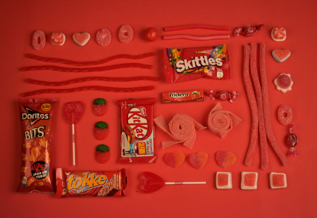 A Captivating Composition: A Playful Assortment of Sweets and Treats Embellishing a Vibrant Red Backdrop, Photographed from Above Wallpaper