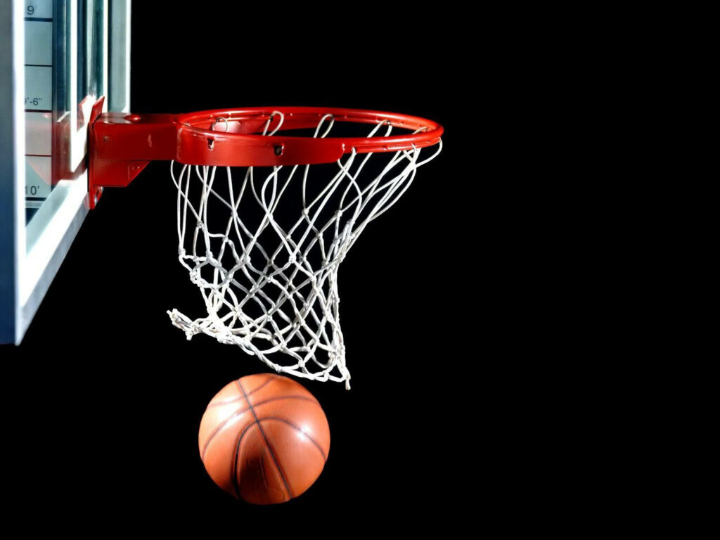 Dunking in Darkness: A Striking Basketball Image with a Ball Piercing the Rim Wallpaper
