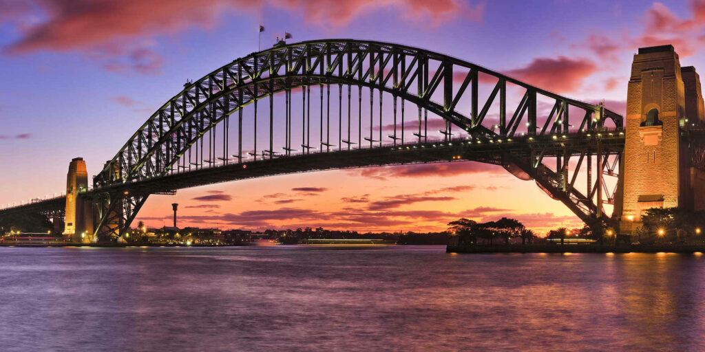 Sydney Harbour Bridge at sunset vibrant sky reflecting on calm water iconic Australian landmark wallpaper