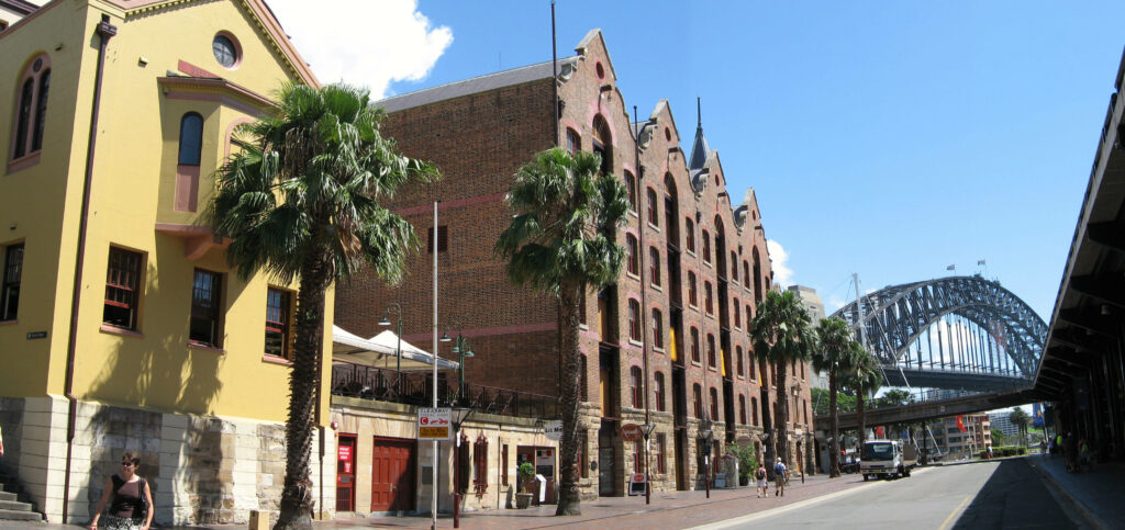 Historic Sydney Rocks district with brick buildings palm trees and Sydney Harbour Bridge view wallpaper
