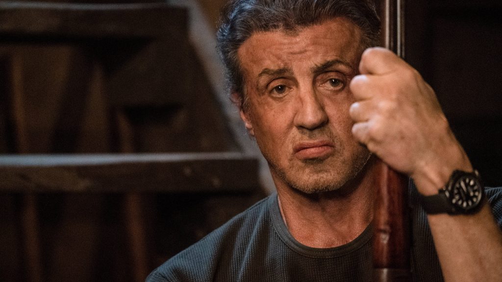 Close-up of Sylvester Stallone as John Rambo holding rifle intense cinematic wallpaper background