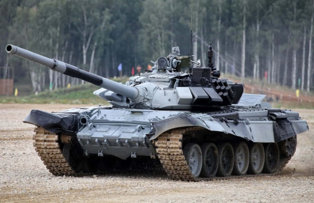 T-72 main battle tank cruising rugged gravel terrain with forest backdrop military wallpaper background