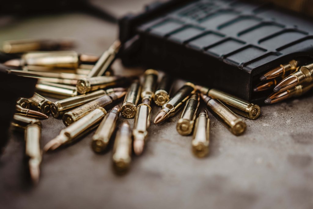 Brass rifle cartridges and polymer magazine with shallow depth of field tactical wallpaper background