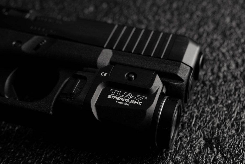 Glock handgun with Streamlight TLR-7 light on black textured background in dramatic lighting Wallpaper