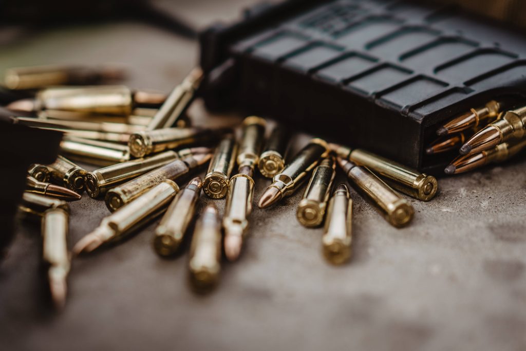 Close-up of scattered 223 caliber brass ammo and polymer rifle magazine on textured surface Wallpaper