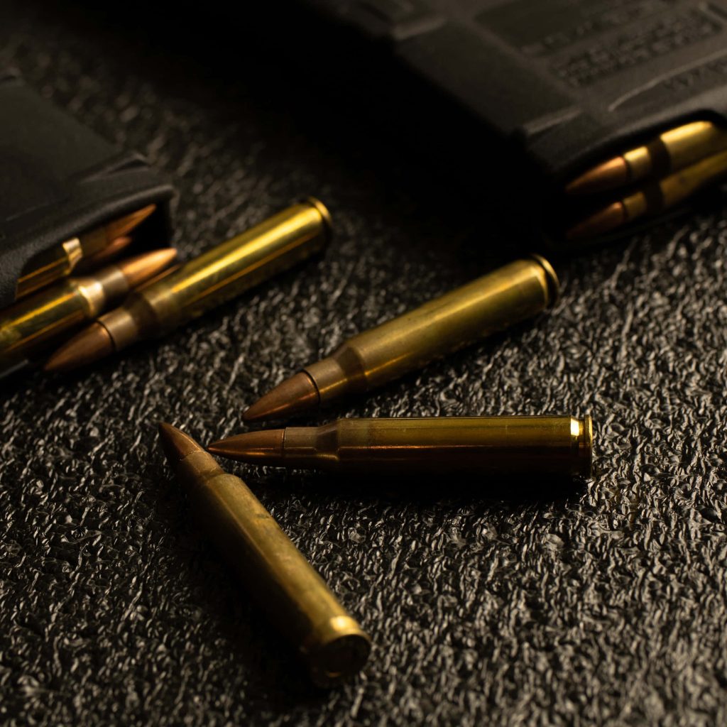 Brass rifle cartridges and black polymer magazines on dark textured surface tactical wallpaper