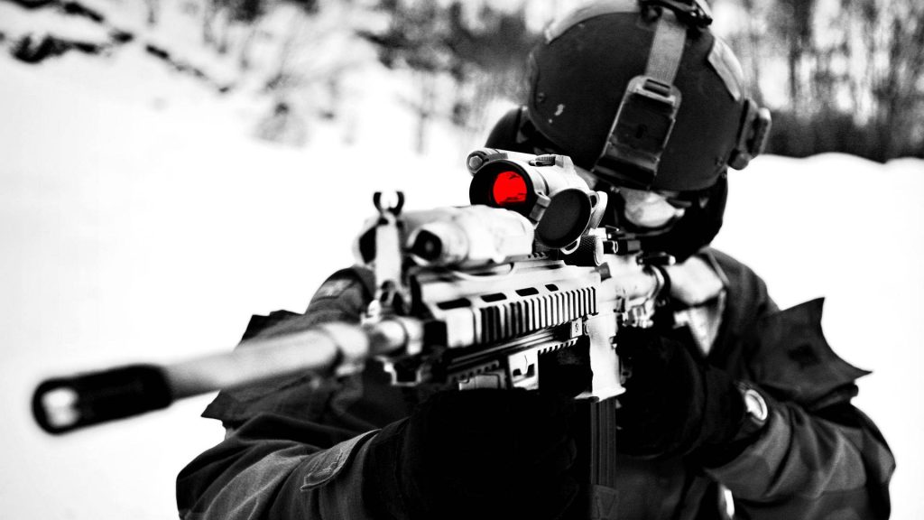 Tactical soldier aims assault rifle with red optic in snowy winter high contrast black and white wallpaper