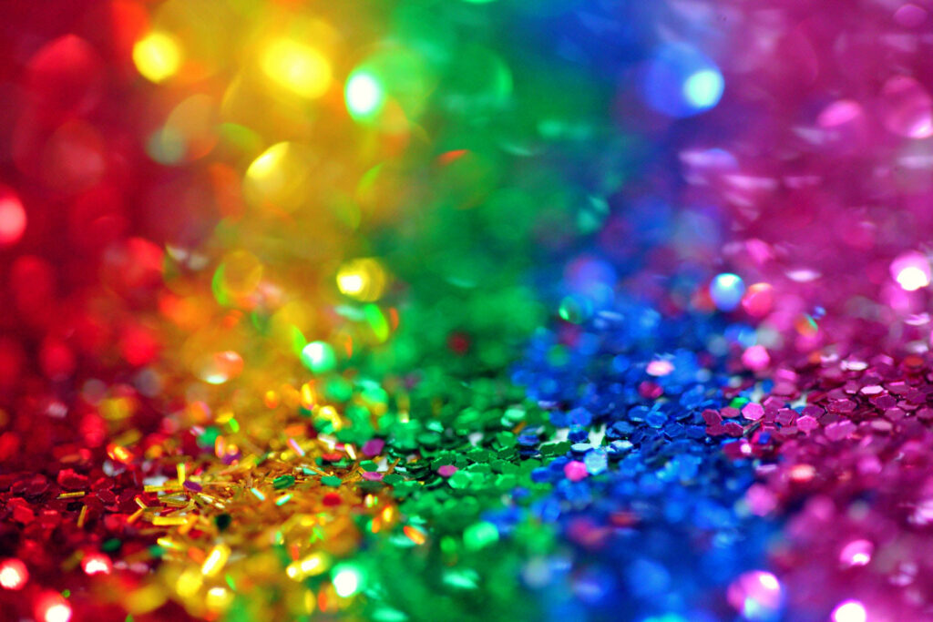 Vibrant rainbow glitter explosion wallpaper with soft bokeh lighting for festive desktop background