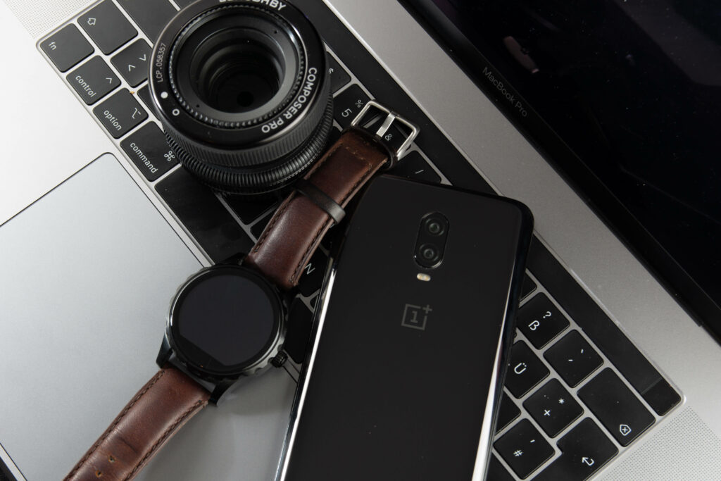 Tech Ensemble: Blending Smartwatch, Phone, and Camera on Polished Laptop Wallpaper