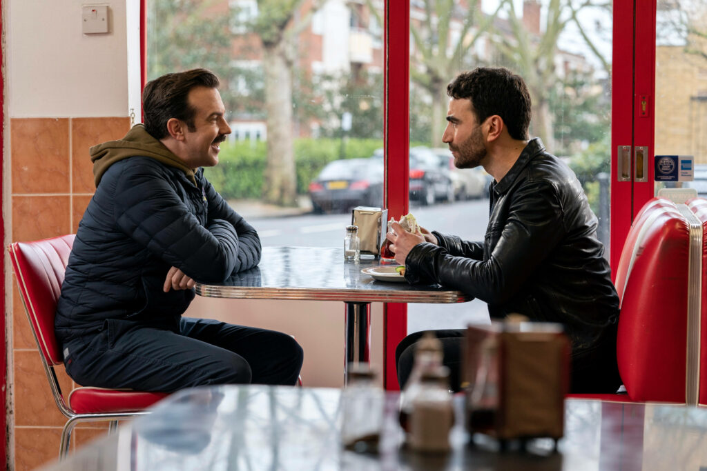 Ted Lasso Chats with Friends in Cozy Fast-Food Restaurant Wallpaper