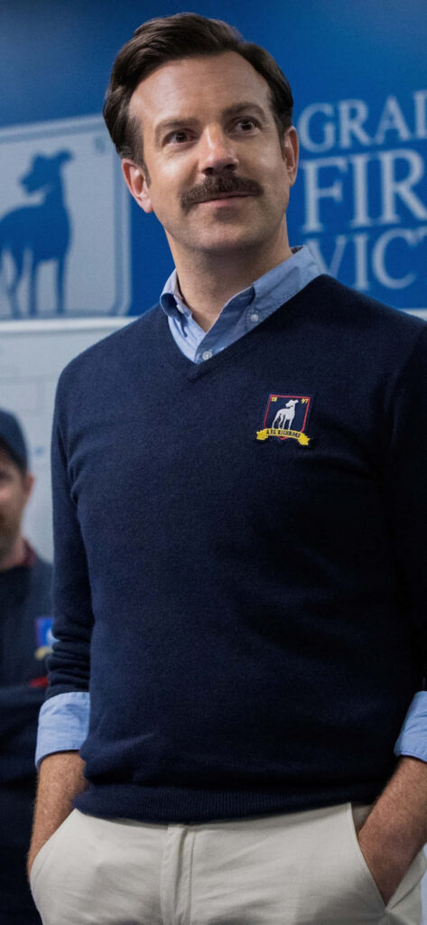 Ted Lasso Smiling Portrait in Stylish Blue Sweater - Wallpaper