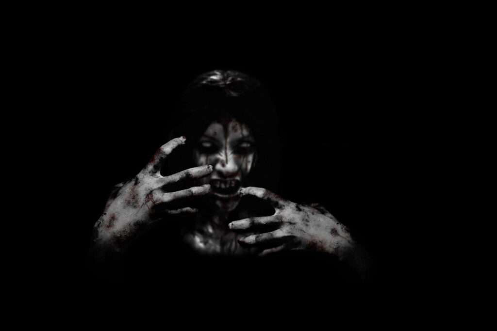 Ghostly figure with menacing hands and haunting smile emerging from dark scary wallpaper background