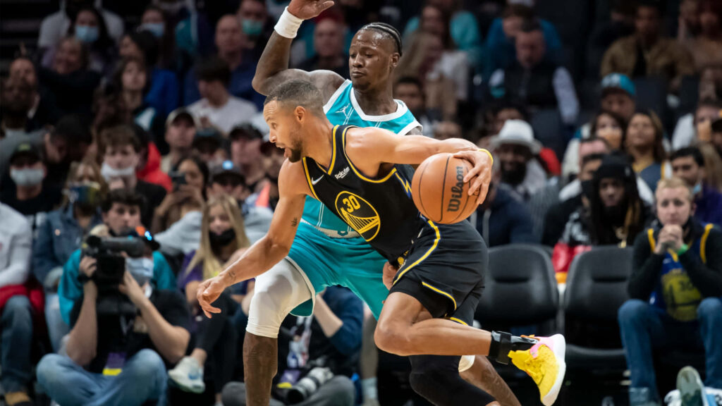 Terry Rozier defends Stephen Curry driving to basket in intense NBA game with vibrant crowd Wallpaper