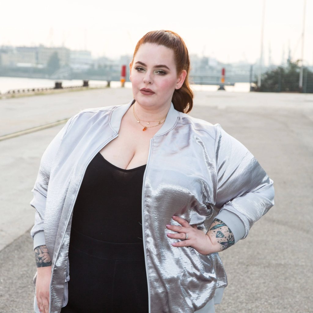 Tess Holliday confident pose metallic silver bomber jacket tattoos industrial harbor background Wallpaper