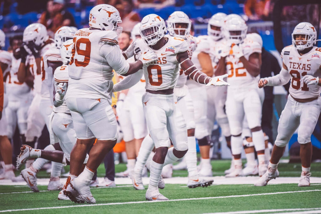 Texas Longhorns football players celebrating on field in white and burnt orange uniforms wallpaper