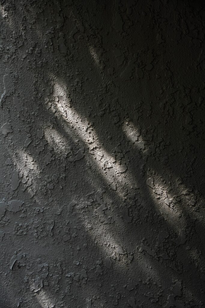 Textured Black and White Plaster Wall Wallpaper with Subtle Light Rays