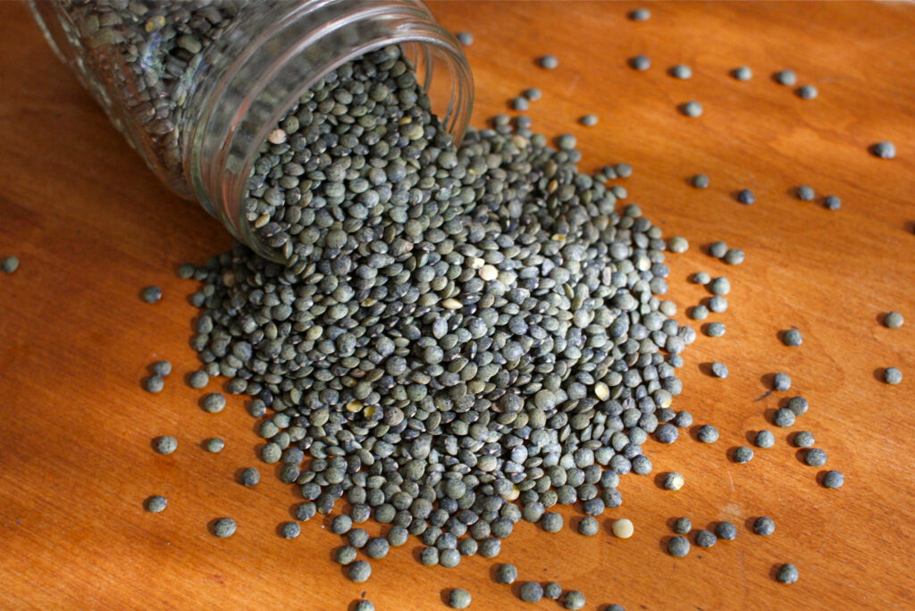 Textured Green Lentils Spilled on Wood: Nature's Wallpaper Background