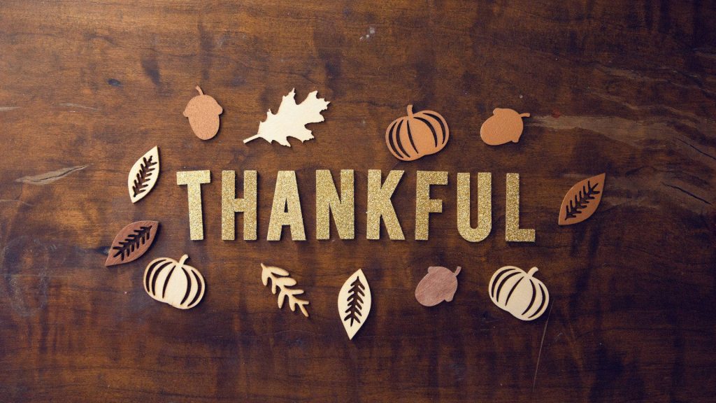 Thankful in gold glitter on rustic wood with pumpkins acorns and fall leaves Thanksgiving wallpaper