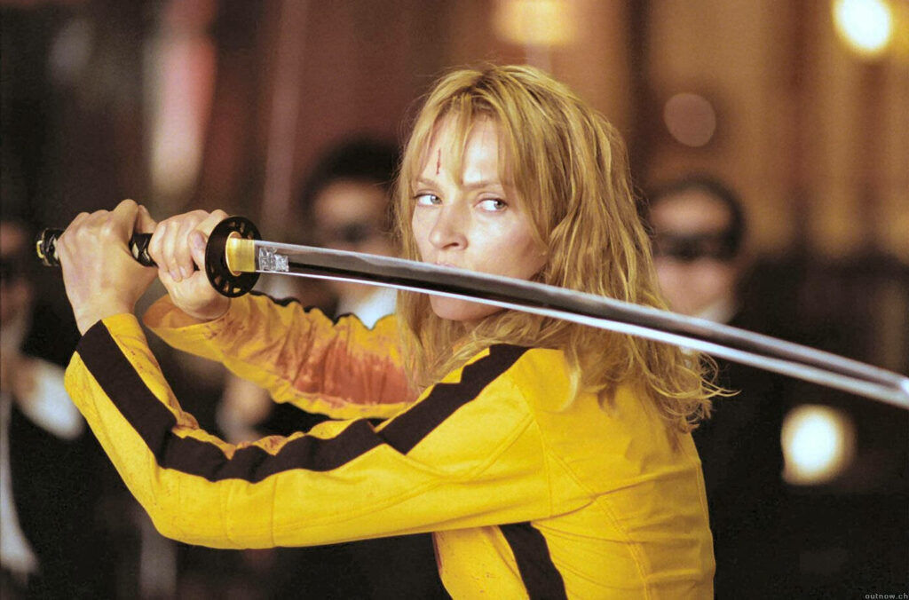 The Bride from Kill Bill in yellow jumpsuit wielding katana in intense fight scene wallpaper