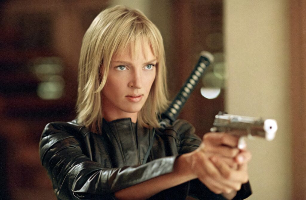 The Bride from Kill Bill in black leather aiming gun with katana on back action wallpaper