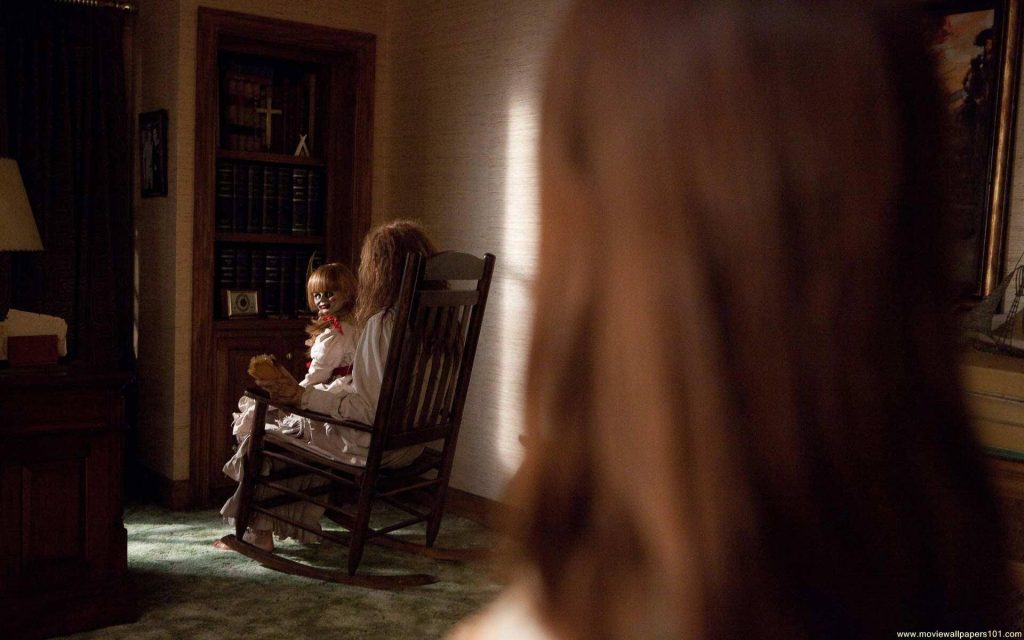 The Conjuring wallpaper featuring possessed Annabelle doll on rocking chair in dim room
