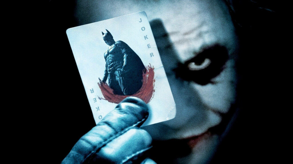 The Dark Knight Deal: Black Ultra HD Joker Holds Batman Card with Smirk on Background Photo Wallpaper
