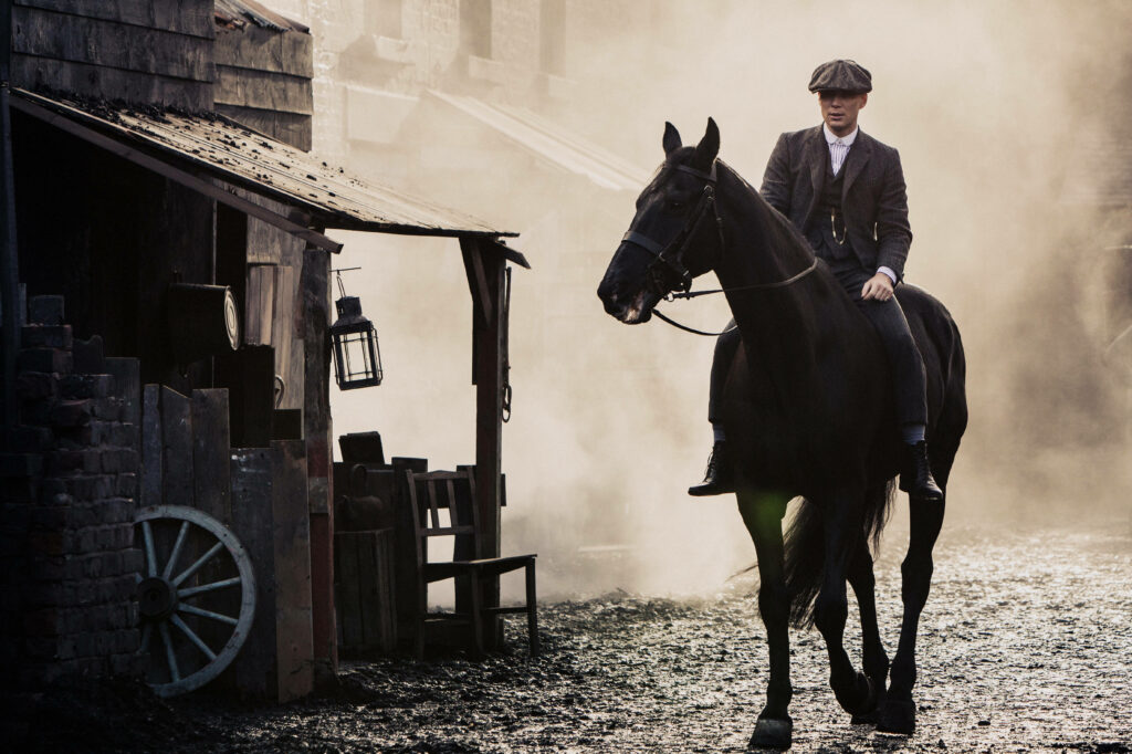 The Dashing Tommy Shelby Gallops on His Majestic Black Stallion - Captivating Peaky Blinders 8k Backdrop Wallpaper
