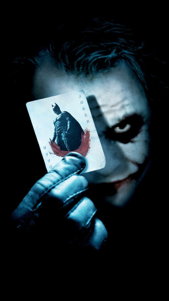 The Menace Lurking in the Shadows: Heath Ledger's Chilling Joker Emerges, Brandishing a Batman Card Wallpaper