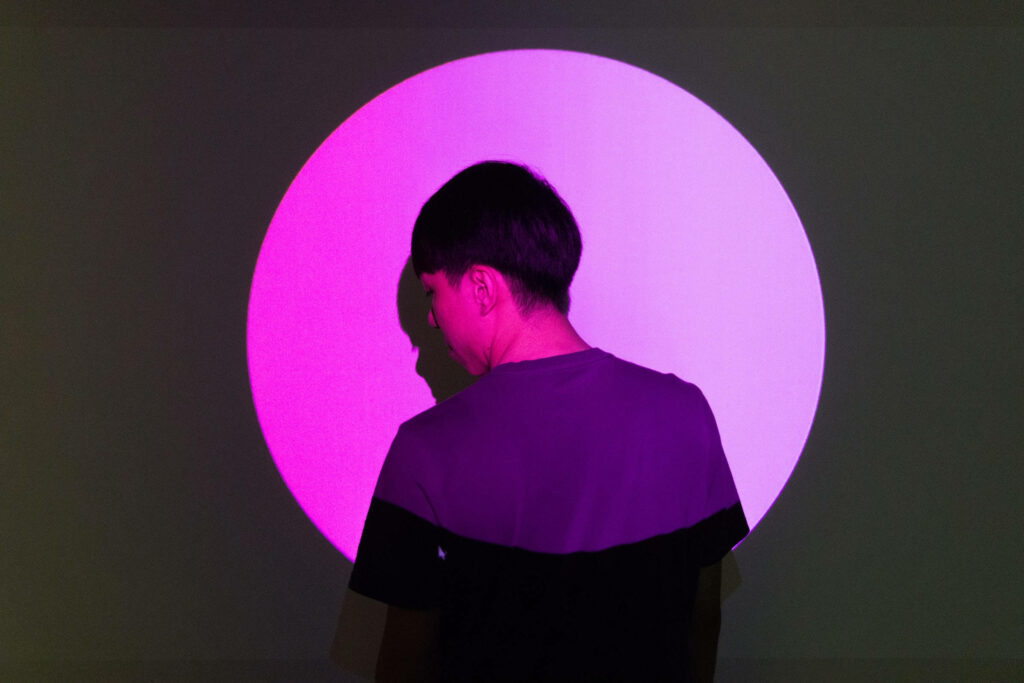 The Pink Spotlight: A Mysterious Profile Beckons in the Shadowy Landscape Wallpaper