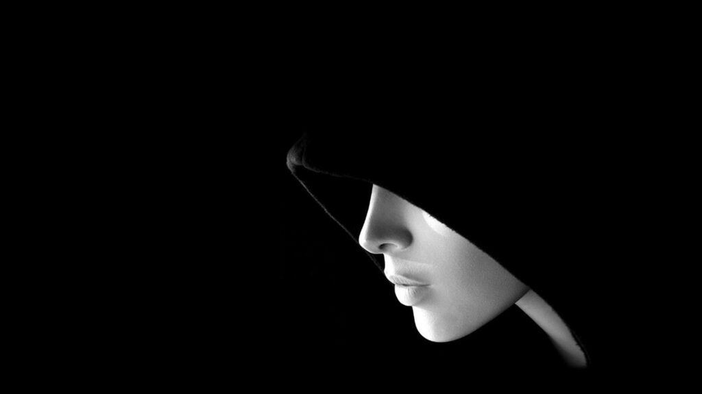 Menacing Melancholy: Hypnotic Portrait of a Mysterious Hooded Woman against a Sinister Void Wallpaper