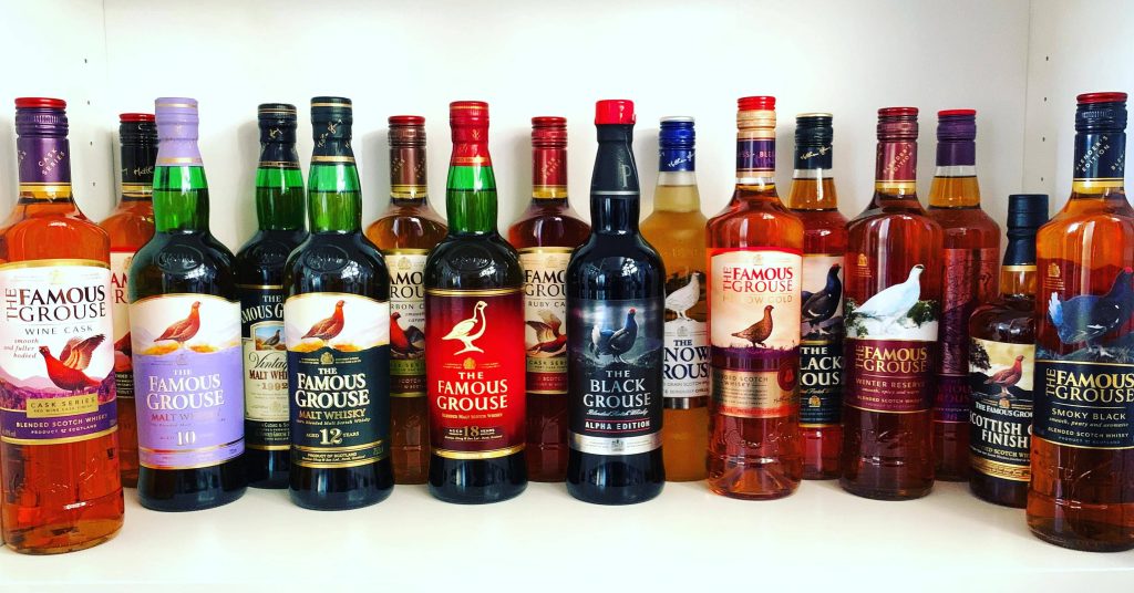The Famous Grouse Whisky collection on white shelf featuring 12 Year 18 Year Black Grouse bottles Wallpaper