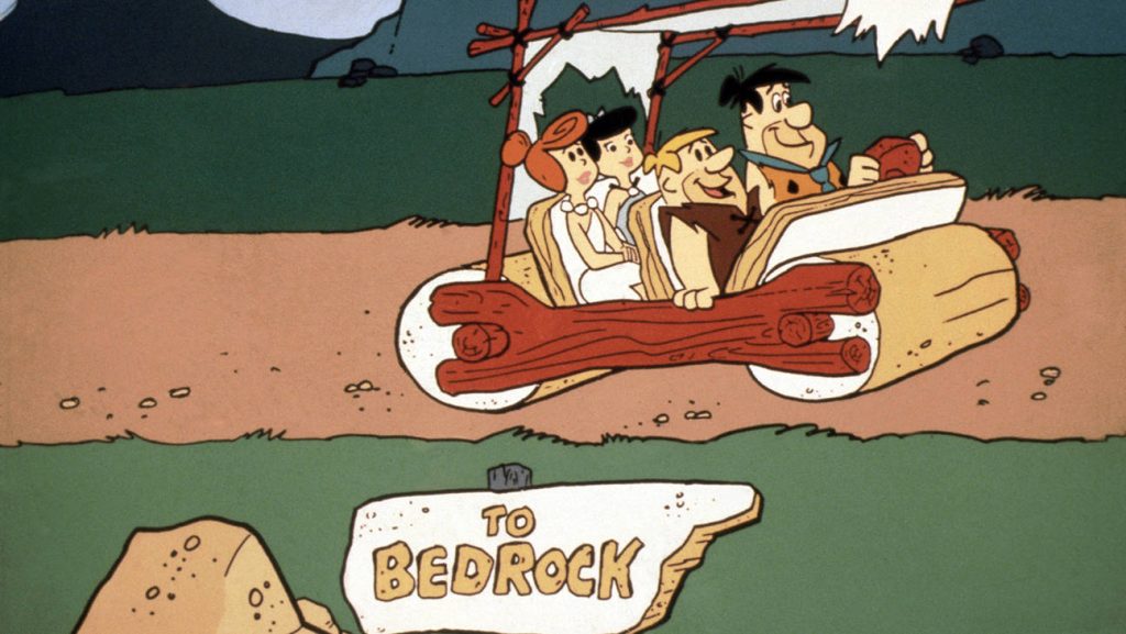 The Flintstones driving stone-age car past Bedrock sign nostalgic classic cartoon wallpaper background