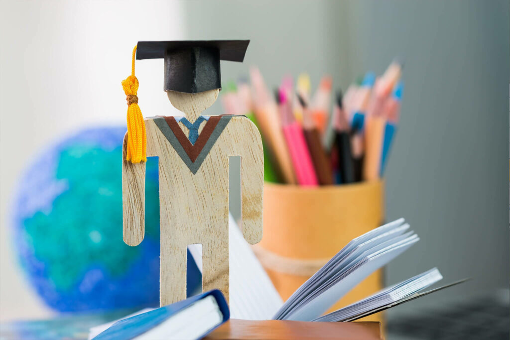 Academic Achievement on a Colorful Canvas: A Popsicle Student Graduates in a Scholarly Setting Wallpaper