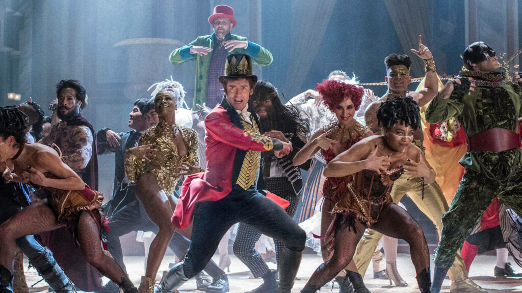 The Greatest Showman wallpaper showing P.T. Barnum and performers in dynamic performance battle