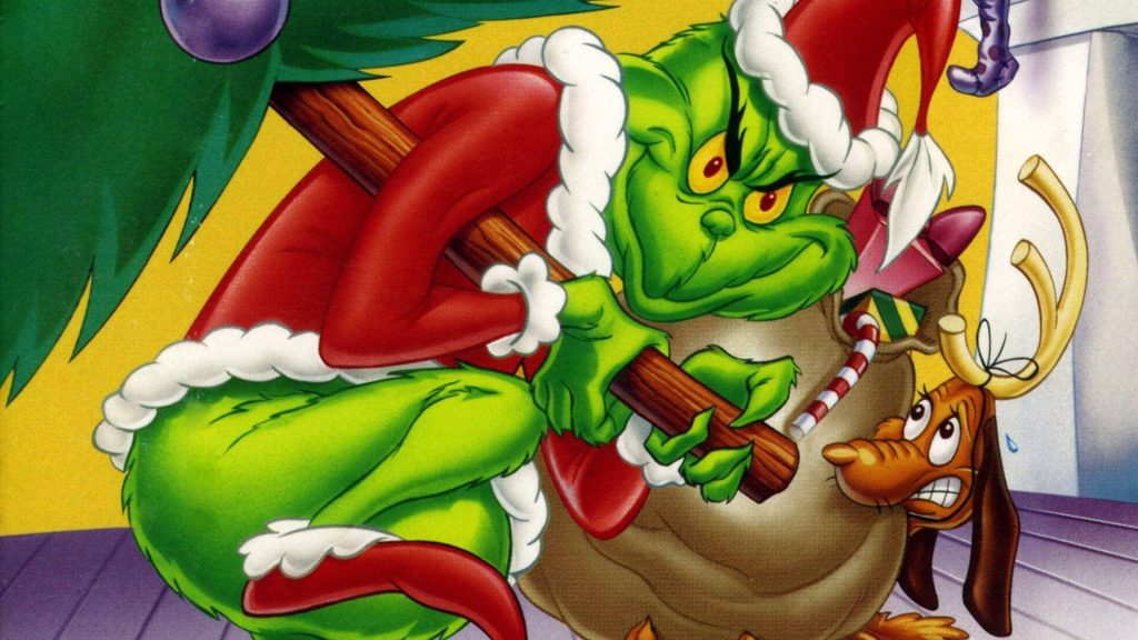 The Grinch in Santa suit sneaking Christmas tree with dog Max in reindeer antlers yellow background Wallpaper