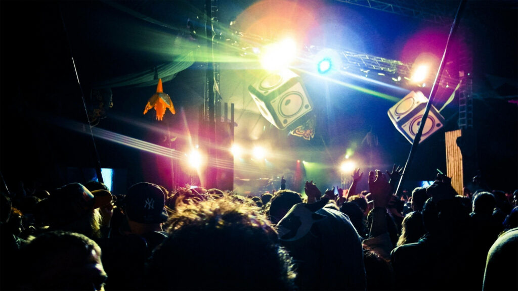 Nighttime live music festival crowd cheers under vibrant neon lights and floating stage sets Wallpaper