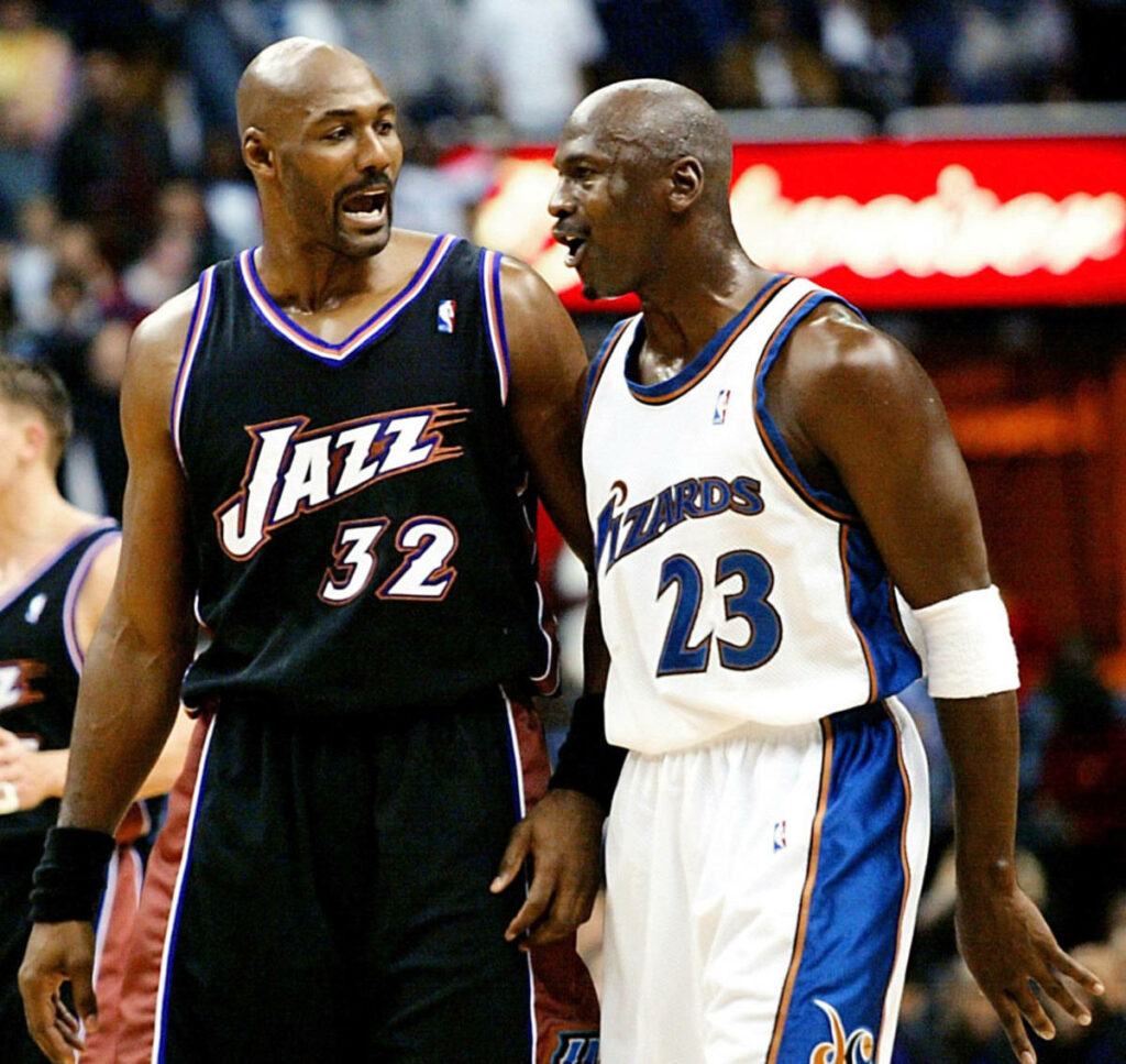 Legendary NBA Icons Karl Malone and Michael Jordan Engage in Intense Hoops Conversation Wallpaper