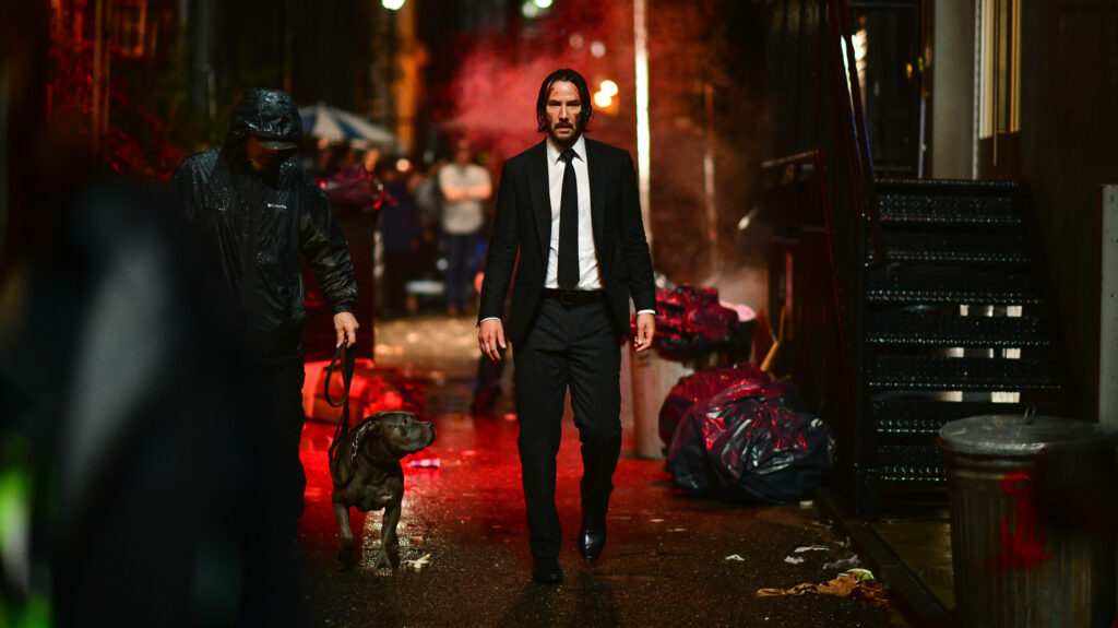 Keanu Reeves embodies the inimitable John Wick, lurking in the shadows of a gritty alleyway - Captivating 5k HD Still from John Wick 3 Set Wallpaper