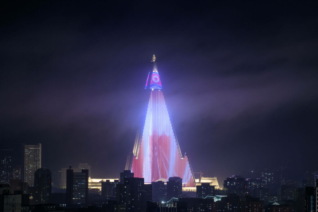 Pyongyang's Iconic Ryugyong Hotel Illuminated by North Korean Flag: Majestic Pyramid Tower Piercing the Night Skyline Wallpaper