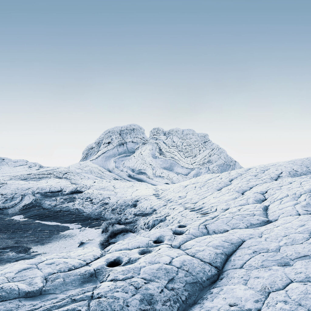 White Pocket sandstone formations in Arizona with textured white rocks under soft blue sky background Wallpaper