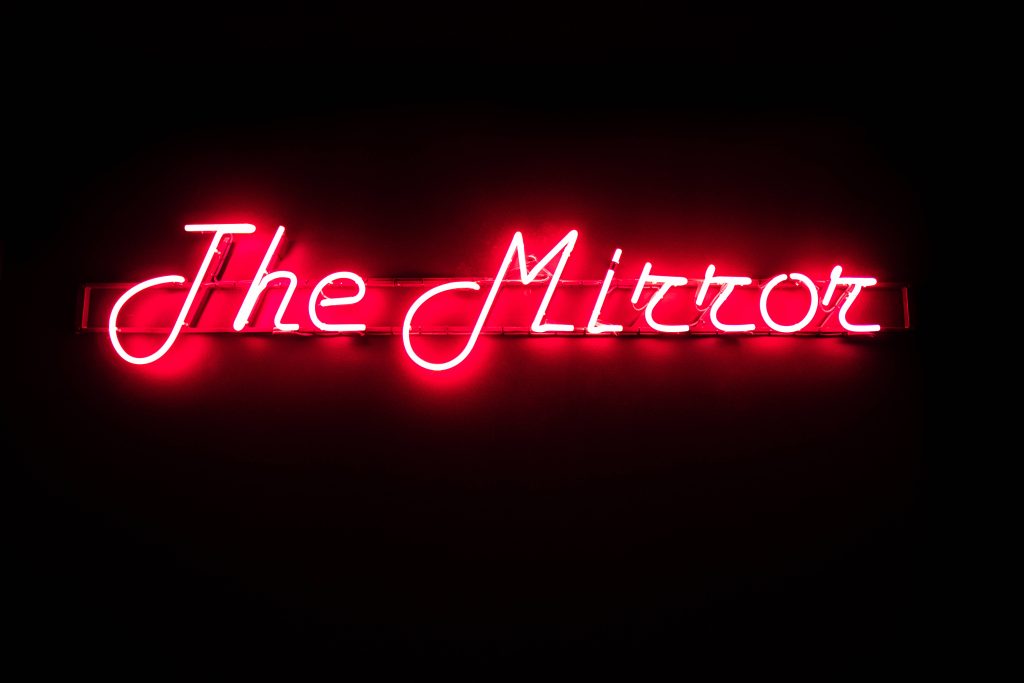 Red neon light wallpaper The Mirror script font on black background minimalist modern decor