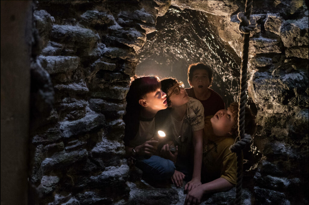 The Losers' Mysterious Gaze: A Still Wallpaper of Bill, Richie, Eddie, and Ben Peeking at the Well in the It Thriller Movie Scene