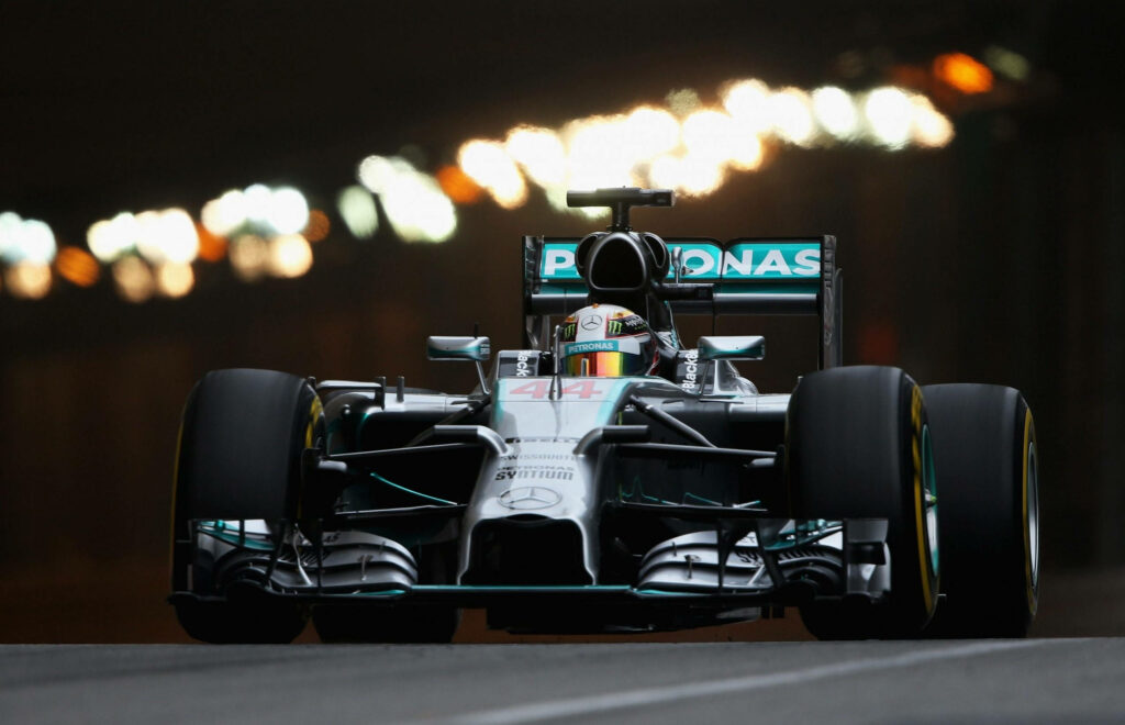 Nighttime Speed: Lewis Hamilton's F1 Racing Car Illuminates the Road in Spectacular Fashion Wallpaper