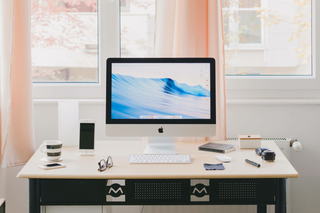 Elevated Workspace: Apple Computer, Books, and Refreshing Beverages in a Peachy Office Atmosphere Wallpaper